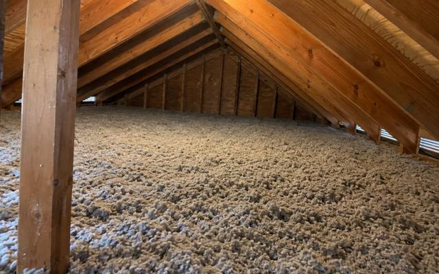 Deep grey cellulose topped up across the attic joists, with eave vents along the right side