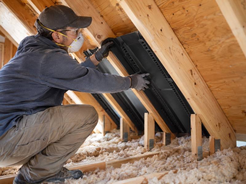 Installer fitting a ventilation baffle between the rafters at the eaves of an attic in Orléans